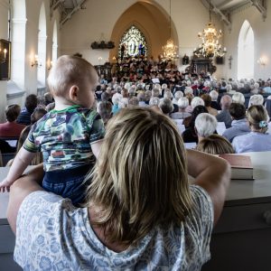 En litet barn tittar ut över överfull kyrka